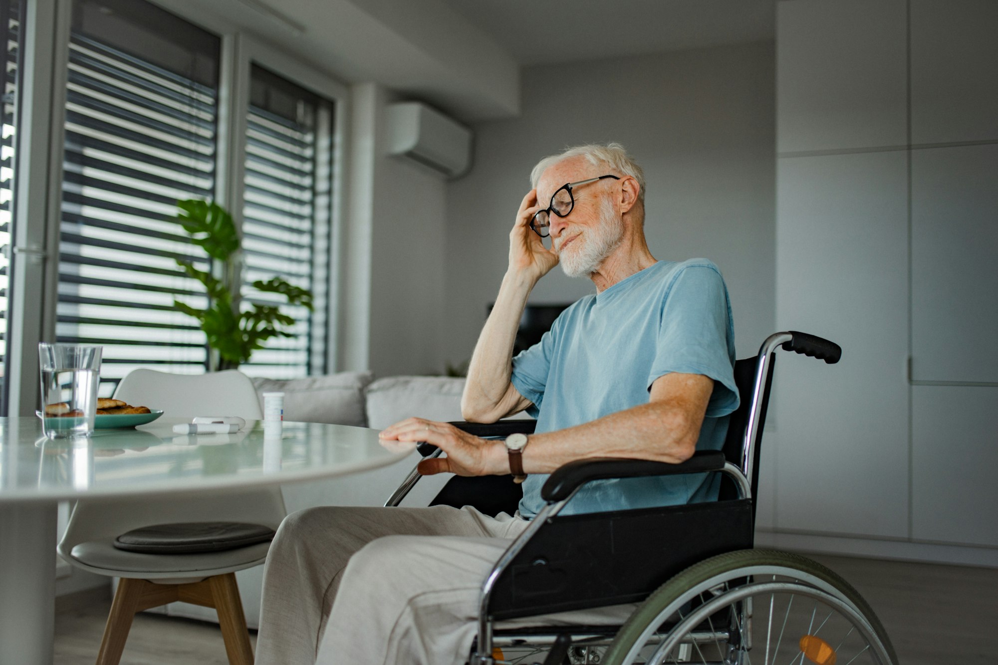 Senior man in wheelchair taking pills at home, he is confused about mediacation usage. Chronically