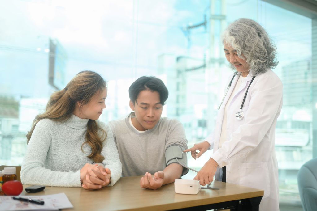 Senior doctor checking blood pressure of a teenage boy.