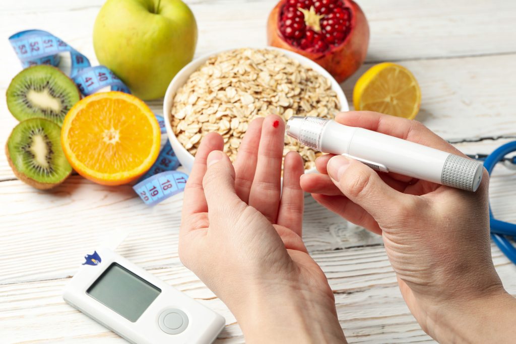 Woman checking her blood sugar level, with healthy foods on background.