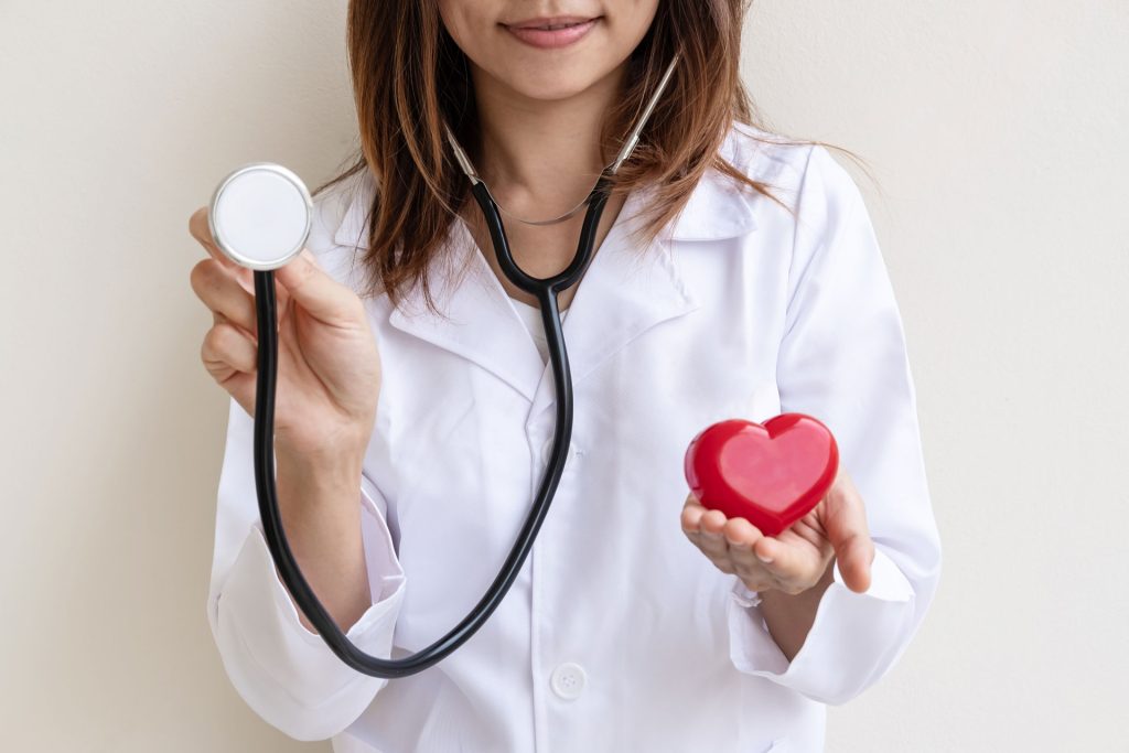Young female doctor holding a stethoscope and heart model.
