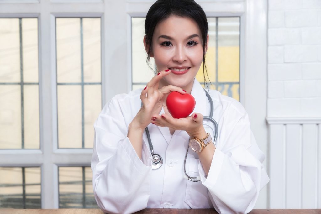 Female doctor holding a red heart ball.