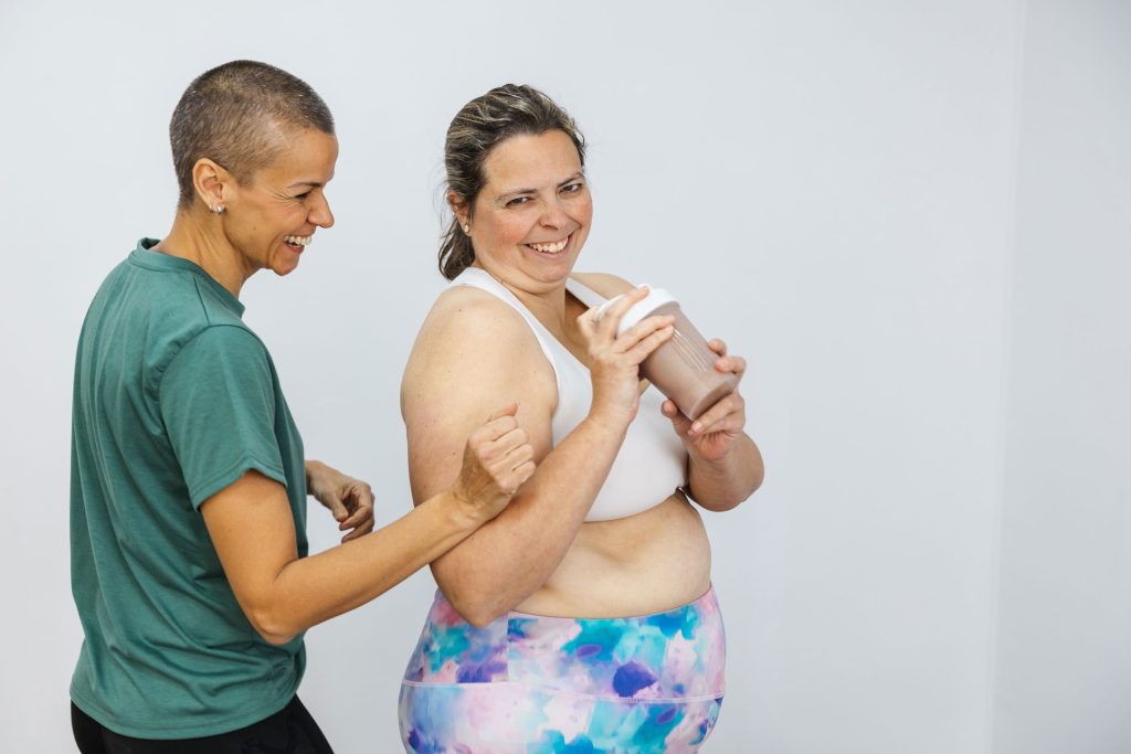 Personal trainer supporting client with protein shake.